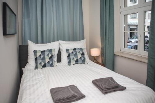 a bedroom with a white bed with pillows and a window at Sleepwell Apartment - Emilienblick in Leipzig