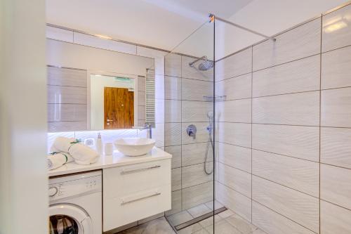 een badkamer met een douche, een wastafel en een wasmachine bij Apartamenty Silver 6 in Szczecin