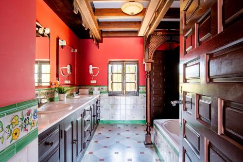 łazienka z 2 umywalkami, wanną i czerwonymi ścianami w obiekcie La Rejaquera w mieście Villanueva del Río y Minas