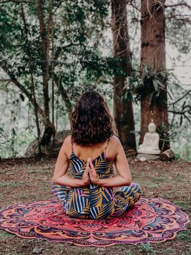 a woman sitting in a meditation pose in a forest at Pousada Quinta das Nascentes in Petrópolis