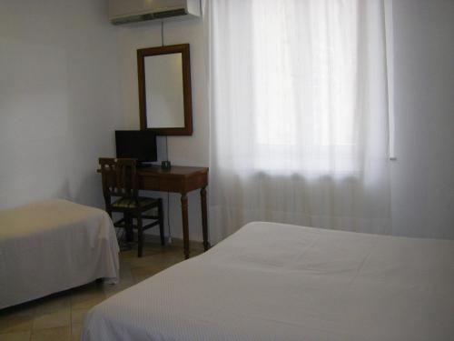 a bedroom with two beds and a desk and a mirror at Albergo Cannon d'Oro in Siena