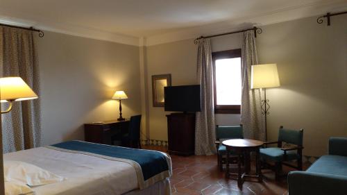 a hotel room with a bed and a table and chairs at Parador de Alcañiz in Alcañiz