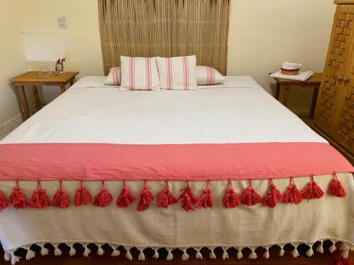 Un dormitorio con una cama con sábanas y almohadas rojas y blancas. en Terraza Cielito Lindo en Oaxaca de Juárez