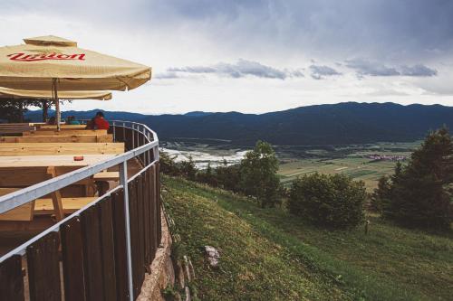 a person sitting on a bench under an umbrella at Dom na Slivnici in Cerknica
