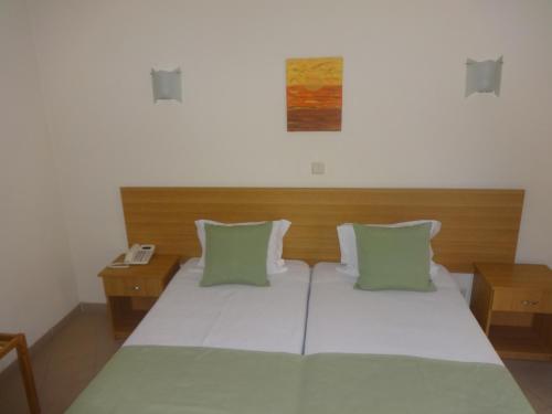 1 dormitorio con 1 cama grande con almohadas verdes en Hotel Bonjardim, en Tomar