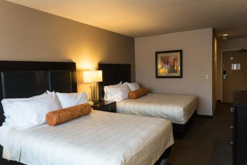 Habitación de hotel con 2 camas con sábanas blancas en Monarch Hotel & Conference Center, en Clackamas