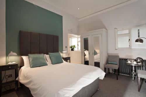 una camera da letto con un grande letto bianco con pareti verdi di Black Rock House a Hastings