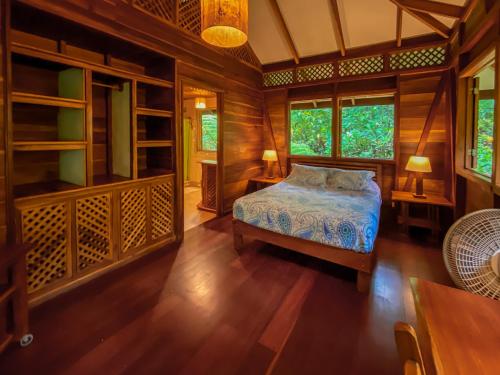 a bedroom with a bed and some windows and a table at Finca Chica Lodge & Villas in Puerto Viejo