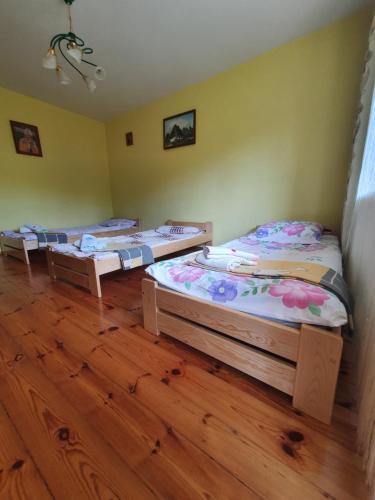 three beds in a room with wooden floors at Agroturystyka LAS i WODA in Prażmów