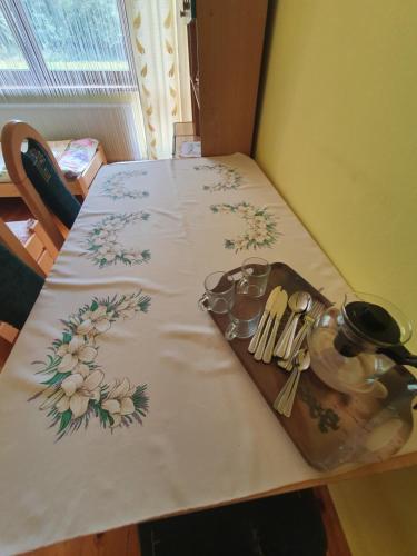 a table with a white table cloth with flowers on it at Agroturystyka LAS i WODA in Prażmów