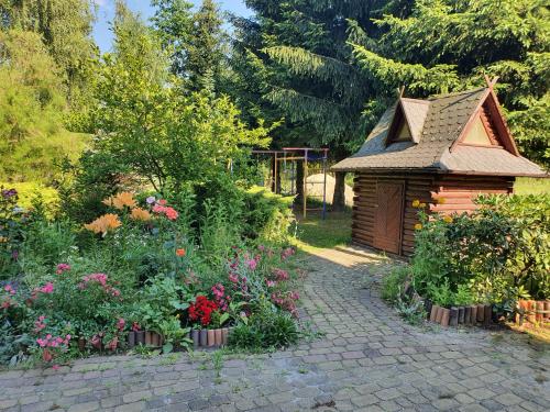 a garden with a small wooden house and flowers at Agroturystyka LAS i WODA in Prażmów