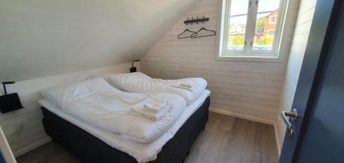 a bed with white sheets in a room with a window at Andøy Vest Rorbuer Reine in Reine