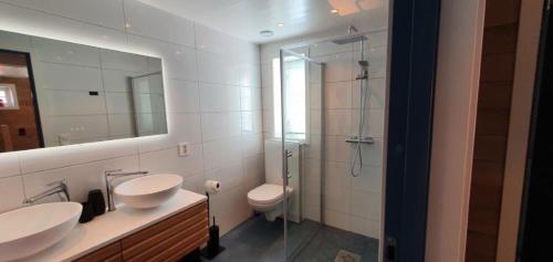 a bathroom with two sinks and a shower and a toilet at Andøy Vest Rorbuer Reine in Reine