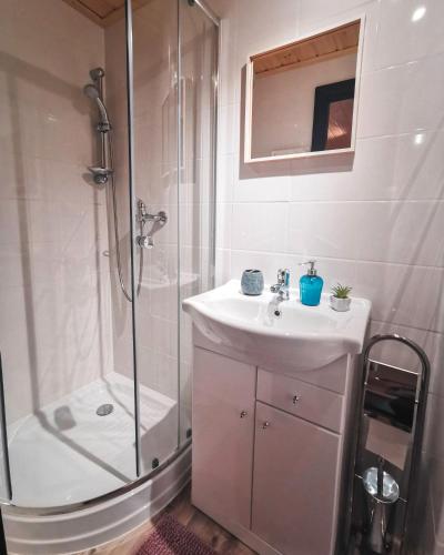 a white bathroom with a shower and a sink at Gästehaus Alpenglühn in Meien