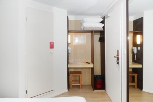 Cette chambre comprend un placard avec des portes blanches et un bureau. dans l'établissement Fasthotel Reims-Taissy, à Reims