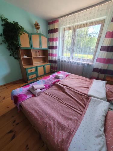 a bedroom with a large bed with pink sheets and a window at Agroturystyka LAS i WODA in Prażmów
