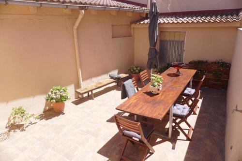 un patio con mesa de madera, sillas y sombrilla en Casa La Solana, en Bolaños de Campos