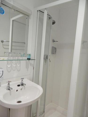 a white bathroom with a sink and a shower at Afton Hotel in Eastbourne