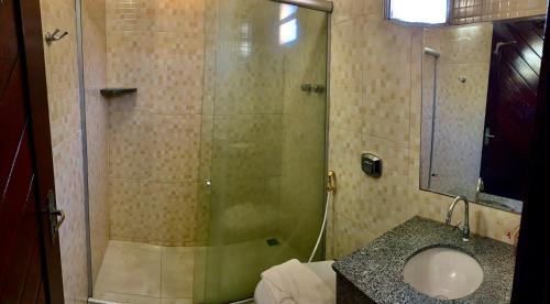 a bathroom with a glass shower with a sink at Pousada Ponta dos Anéis in Maracajaú