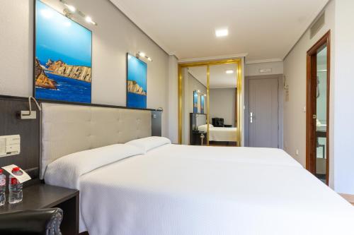 a bedroom with a large white bed and a mirror at Chateau La Roca in Sancibrián
