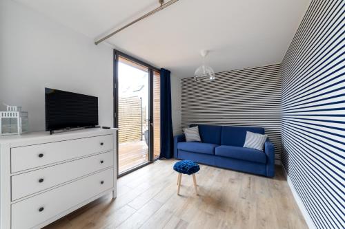 Les Villas de Locmiquel BORD DE MER في بادن: غرفة معيشة مع أريكة زرقاء وتلفزيون