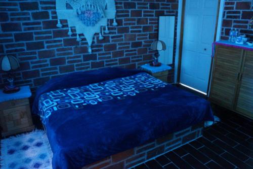 
a bed room with a blue wall and a brick wall at Hotel Casa de la Luna in San Juan Teotihuacán
