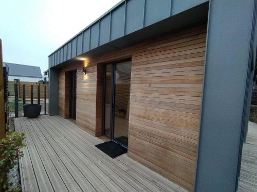 a wooden deck with glass doors on a house at Les Villas de Locmiquel BORD DE MER in Baden