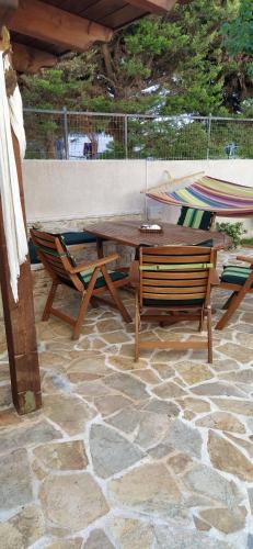 una mesa de madera y sillas en un patio de piedra en Villa Tsios en Artemida