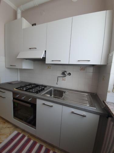a kitchen with white cabinets and a sink at Giolitti Luxury Apartment in Cuneo
