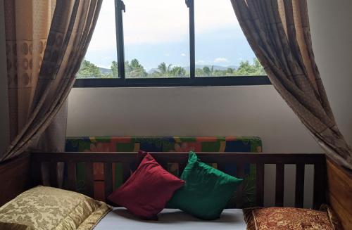 Bett mit zwei Kissen vor dem Fenster in der Unterkunft Cottage Home Belihuloya in Balangoda