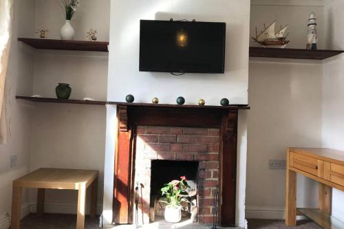 a living room with a fireplace with a television above it at Attractive 2 bed cottage in Hempton Fakenham in Fakenham