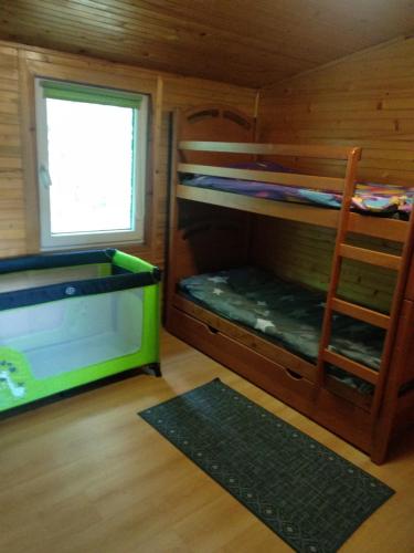 a room with bunk beds with a ladder and a window at Domki Orla na Mazurach in Pasym