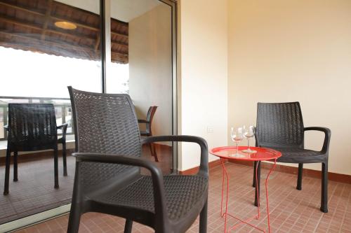 a room with three chairs and a table with wine glasses on it at La Casa Baatsona Apts in Accra