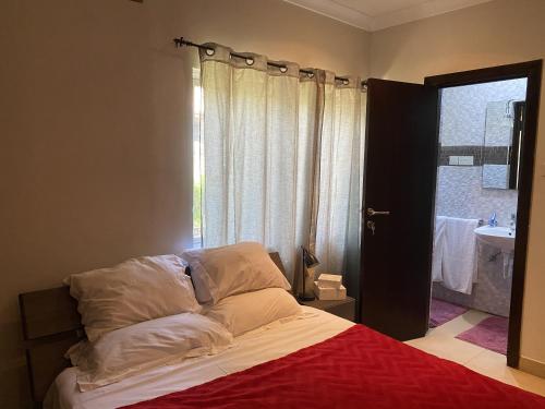 ein Schlafzimmer mit einem Bett, einem Waschbecken und einem Fenster in der Unterkunft [B] Bakerstreet - Beautiful Two Bedroom Apartment in Accra