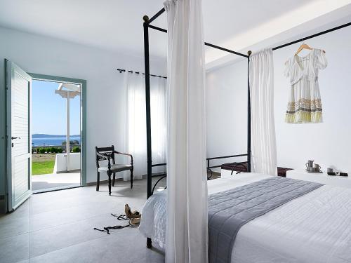 a white bedroom with a bed and a balcony at Santa Maria Luxury Suites & Spa in Adamas