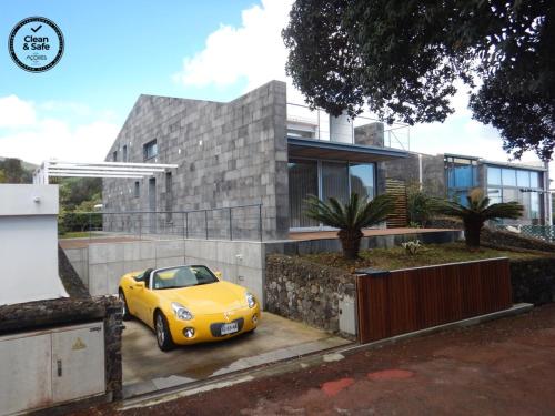 a yellow car parked in front of a house at H. S. Caloura in Lagoa