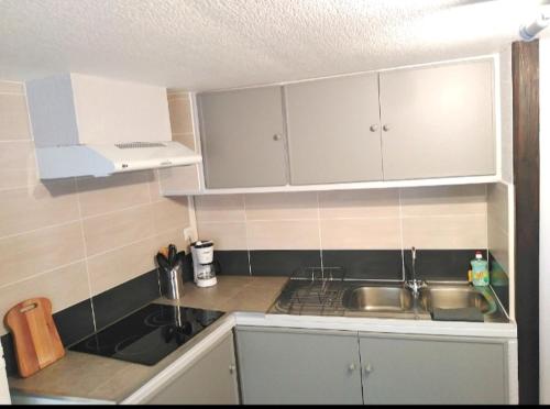 une petite cuisine avec des armoires blanches et un évier dans l'établissement T2 bis quartier château de Pau, à Pau