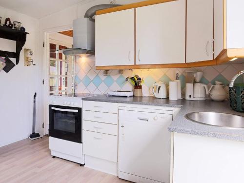 6 person holiday home in G rlev في Gørlev: مطبخ مع دواليب بيضاء ومغسلة