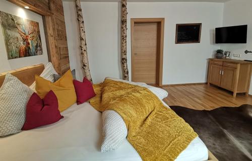 una camera da letto con un letto bianco con cuscini colorati di BERGHEIL Apartments a Schwendau