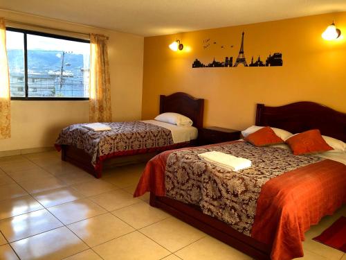 a hotel room with two beds and a window at Hostal Mitad del Mundo in Cayambe