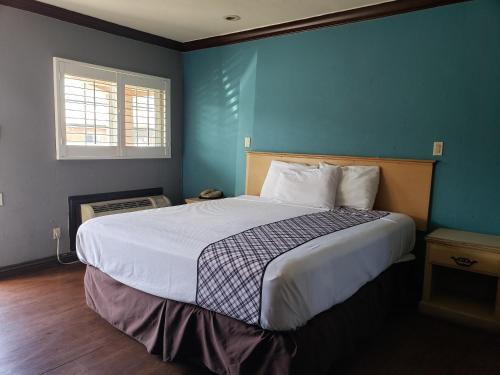 ein Schlafzimmer mit einem großen Bett mit blauer Wand in der Unterkunft Eagle Inn Motel in Long Beach