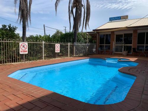 a large blue swimming pool next to a fence at Charleville Motel in Charleville