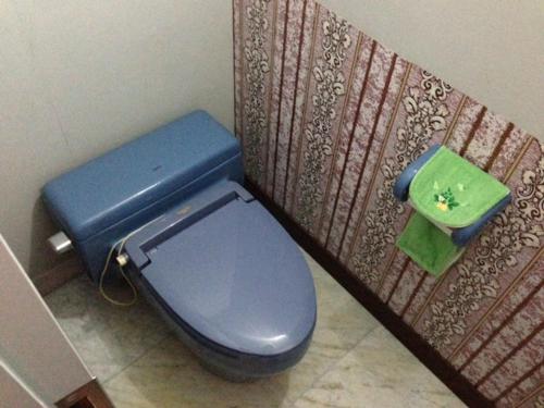a blue toilet in a bathroom with a green box at Narita Airport Samurai Hostel in Kujukuri