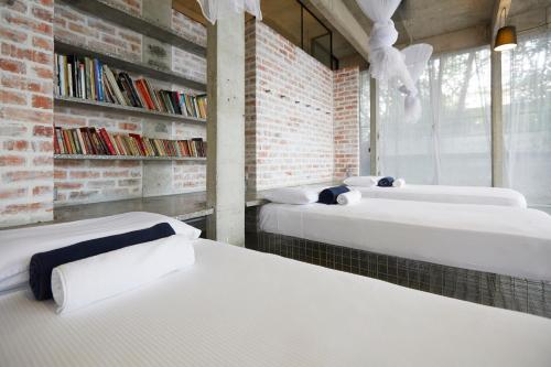 three beds in a room with a brick wall at Belakang KongHeng By DreamScape in Ipoh