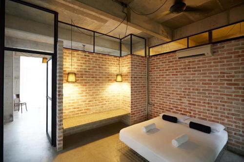 a bedroom with a white bed in a brick wall at Belakang KongHeng By DreamScape in Ipoh