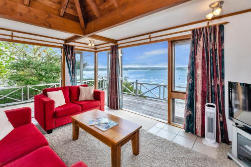 a living room with red furniture and a view of the ocean at Te Maiki Retreat - Russell Holiday Home in Russell