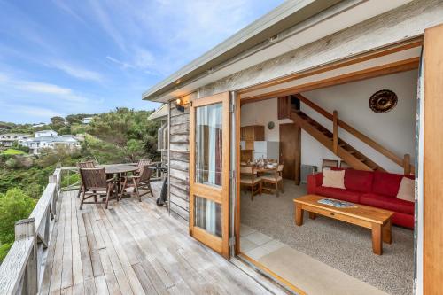 a house with a red couch and a table on a deck at Te Maiki Retreat - Russell Holiday Home in Russell
