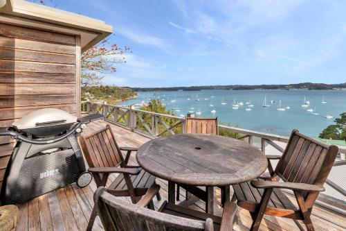 a wooden deck with a table and chairs and a grill at Te Maiki Retreat - Russell Holiday Home in Russell