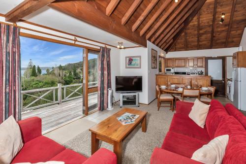 a living room with a red couch and a table at Te Maiki Retreat - Russell Holiday Home in Russell