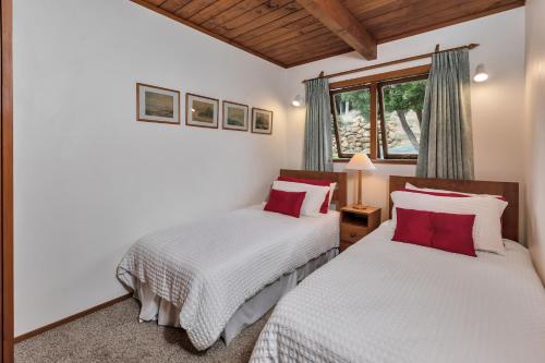 a bedroom with two beds with white and red pillows at Te Maiki Retreat - Russell Holiday Home in Russell